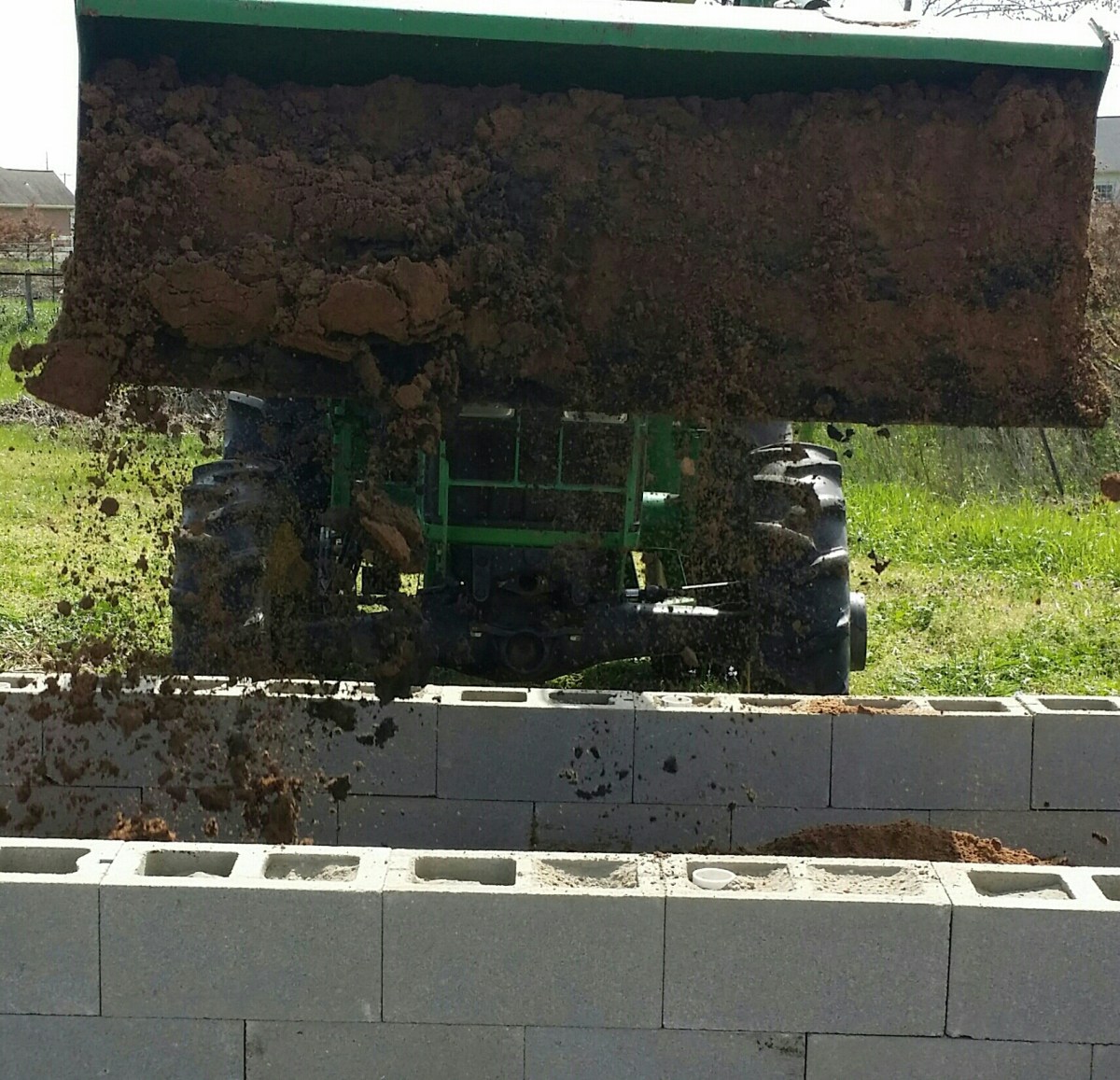 Tractor bucket drops soil into the raised bed.